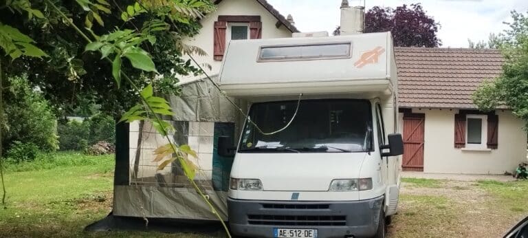 Camping-car blanc avec auvent dans un jardin
