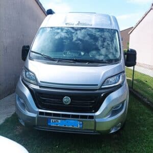 Camping-car argenté garé entre deux murs