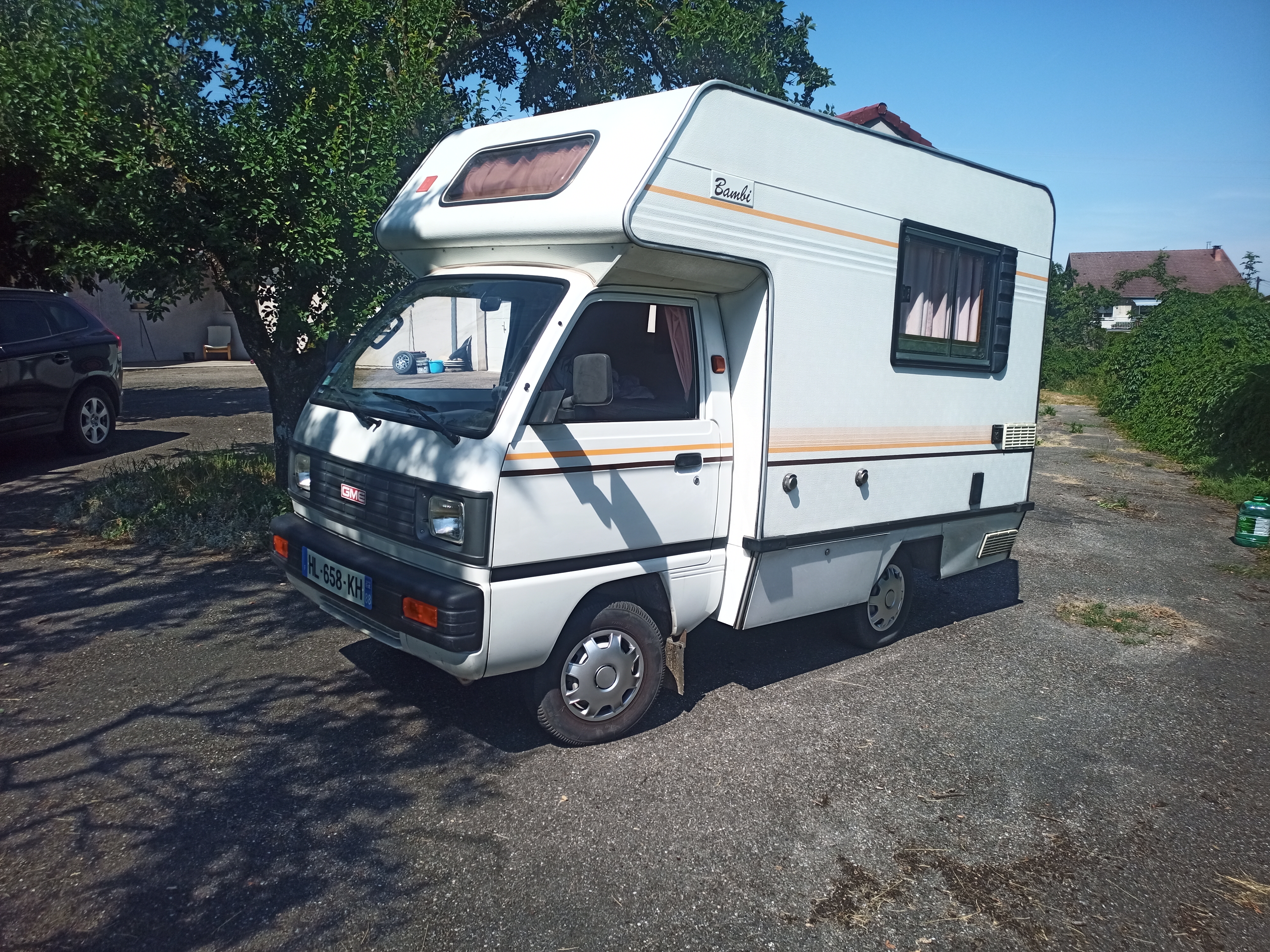Petit camping-car blanc garé près d’une maison