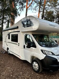 Camping-car blanc stationné sous des arbres