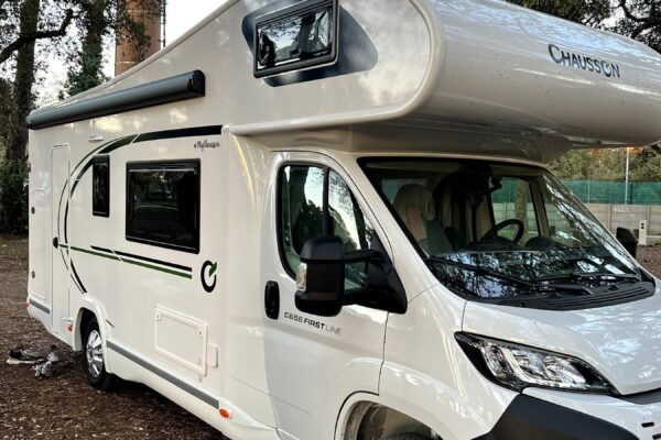 Camping-car blanc stationné sous des arbres
