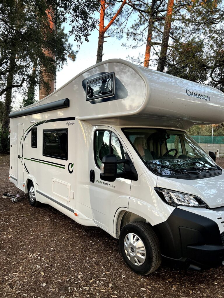 Camping-car blanc stationné sous des arbres