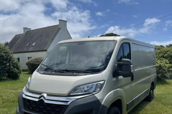 Fourgon beige garé devant maison sous ciel bleu