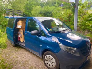 Van aménagé bleu garé dans un jardin