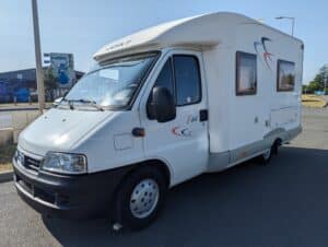 Camping-car blanc stationné en zone commerciale