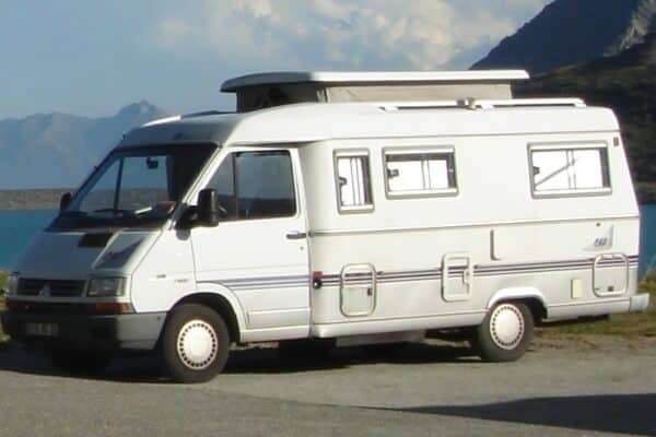 Camping-car blanc au bord d’un lac montagneux