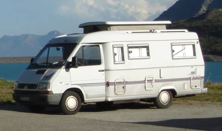 Camping-car blanc au bord d’un lac montagneux