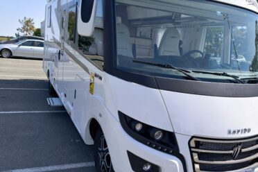 Camping-car Rapido blanc stationné sur parking ensoleillé
