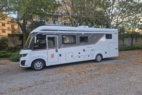 Camping-car blanc stationné près d’arbres en ville