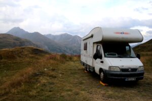 Camping-car stationné en montagne sous ciel nuageux