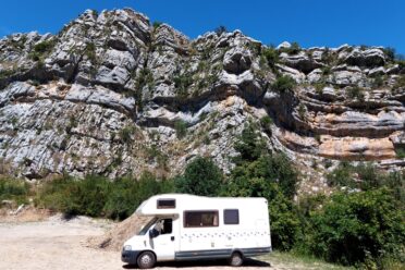 Camping-car blanc au pied de falaises rocheuses
