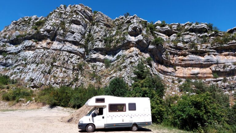 Camping-car blanc au pied de falaises rocheuses