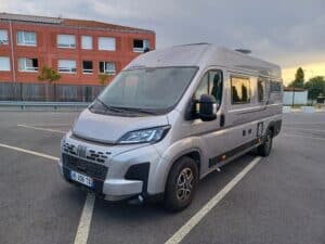 Camping-car Fiat gris stationné au coucher du soleil