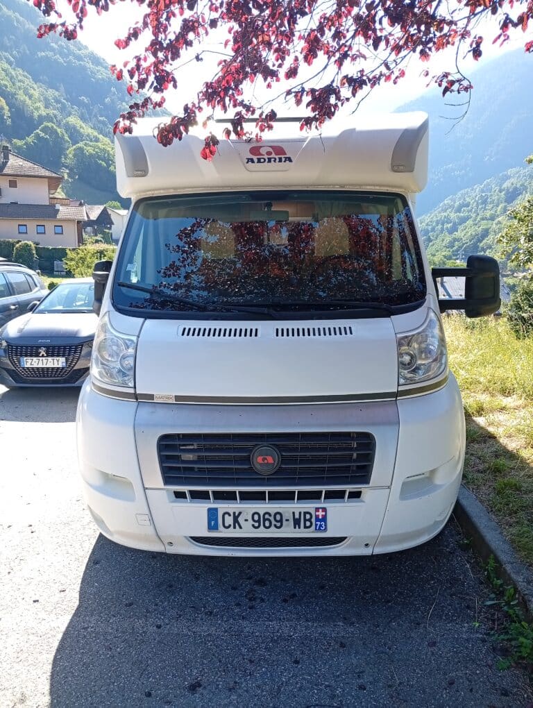 Camping-car blanc en montagne sous feuilles rouges