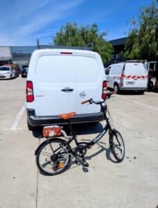 Vélo pliant noir derrière une camionnette blanche