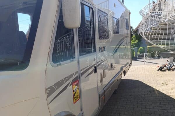 Camping-car blanc garé dans une cour ensoleillée