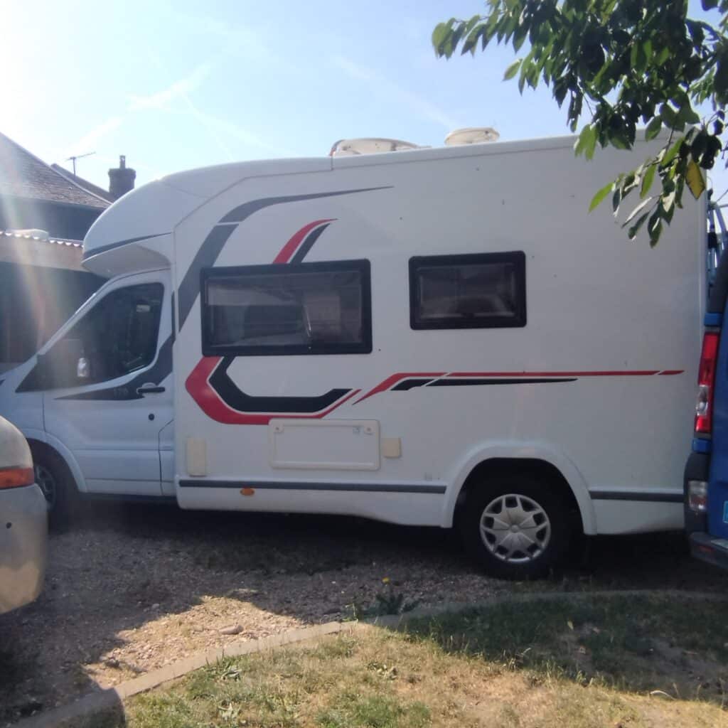 Camping-car blanc garé près d’une maison