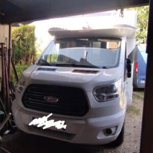 Camping-car blanc stationné sous un abri