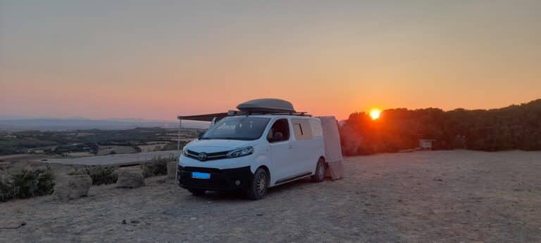 Van aménagé blanc au coucher du soleil