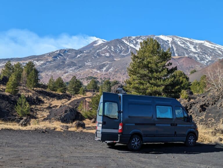 Van aménagé devant volcan enneigé et pins