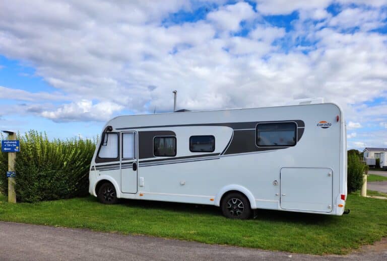 Camping-car blanc stationné sur emplacement verdoyant