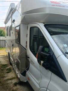 Camping-car blanc stationné près d’une clôture