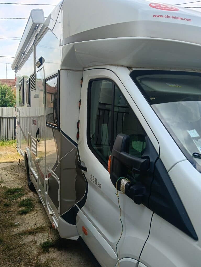 Camping-car blanc stationné près d’une clôture