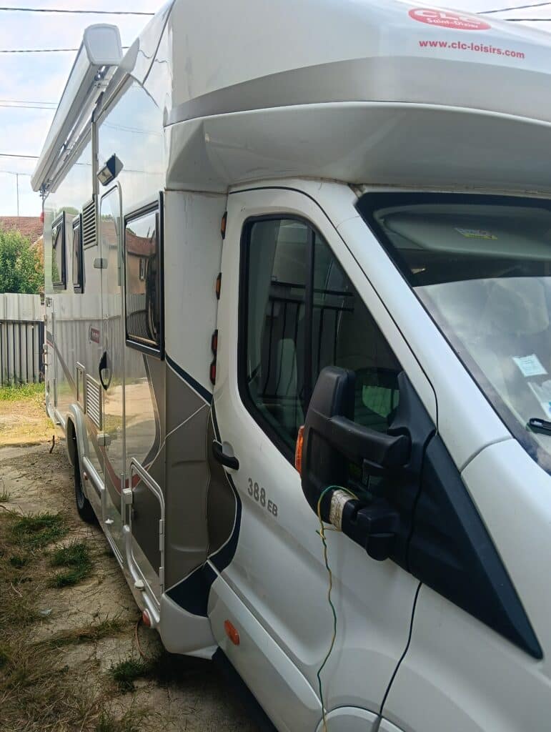 Camping-car blanc stationné près d’une clôture