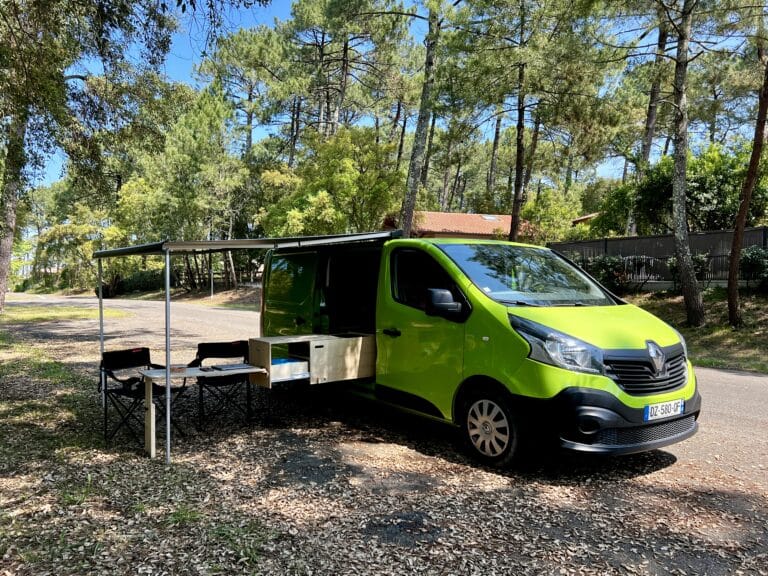 Van aménagé vert avec auvent en forêt