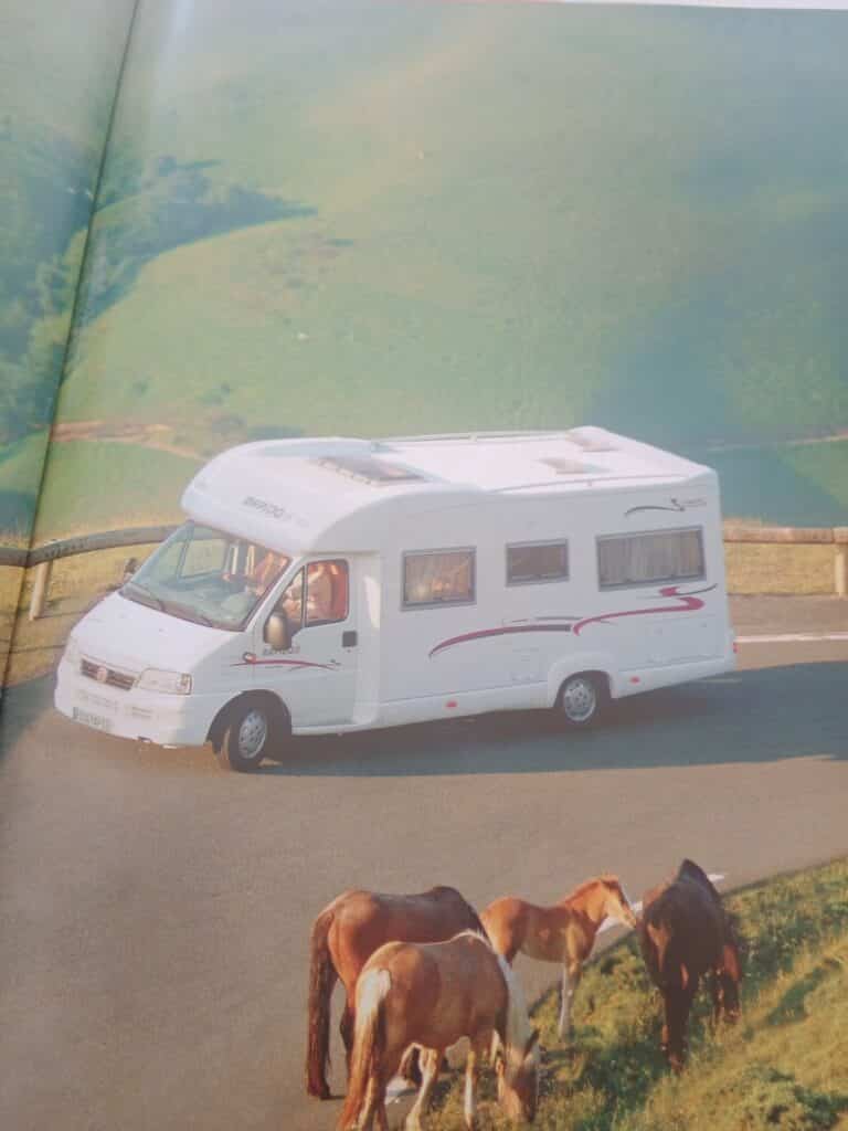 Camping-car blanc sur route, chevaux au premier plan