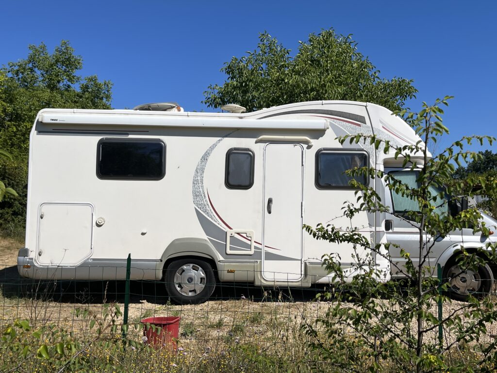 Camping-car blanc stationné près d’arbres