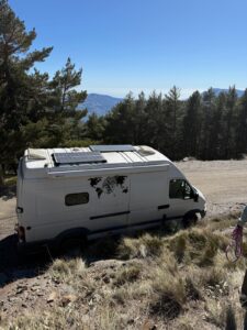 Van aménagé blanc avec panneaux solaires en montagne