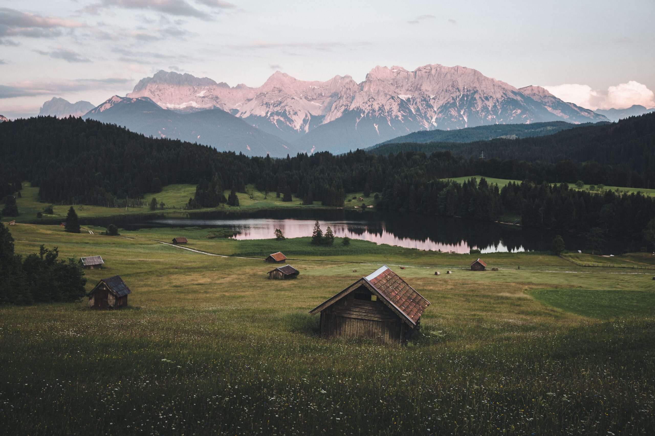 Vallée alpine avec chalets, lac et montagnes brumeuses