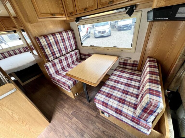 Intérieur de caravane avec banquettes à carreaux rouges.