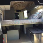 Intérieur d'un van aménagé avec lit et rangement.