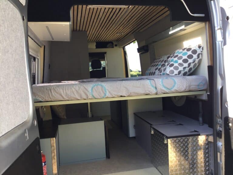 Intérieur d'un van aménagé avec lit et rangement.