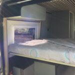 Intérieur d'un van aménagé avec lit et rangement.