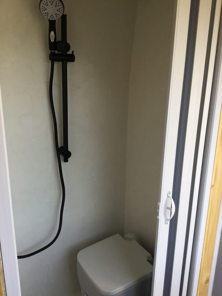 Petit espace douche avec toilettes modernes blanches.