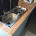 Cuisine compacte avec évier et plaque de cuisson.