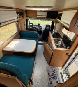 Intérieur d'un camping-car avec cuisine et coin repas.