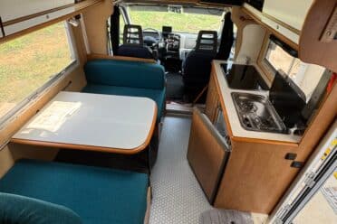 Innenseite eines Wohnmobil mit Küche und Essbereich.