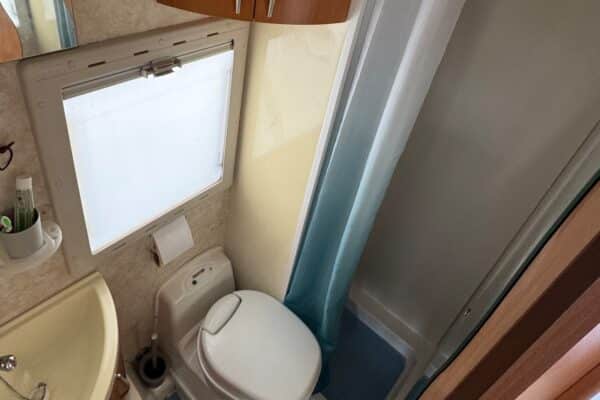 Petite salle de bain avec toilettes et douche.