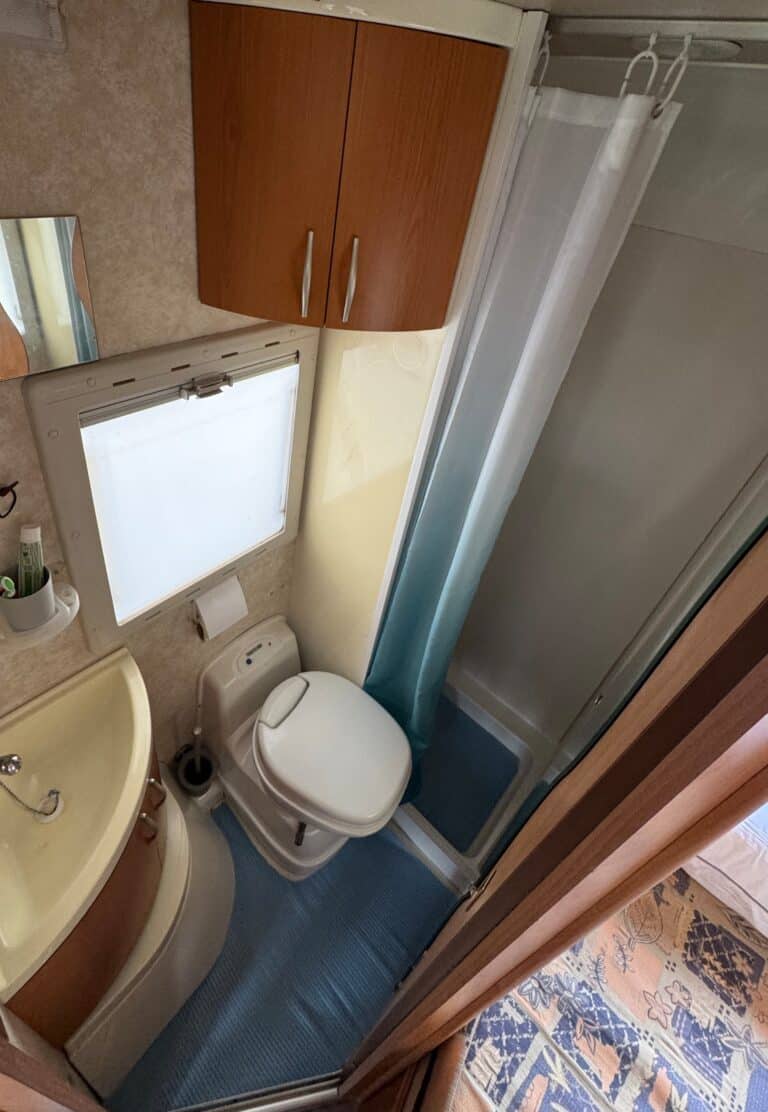 Petite salle de bain avec toilettes et douche.