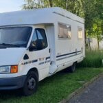 Camping-car blanc garé près de maisons.