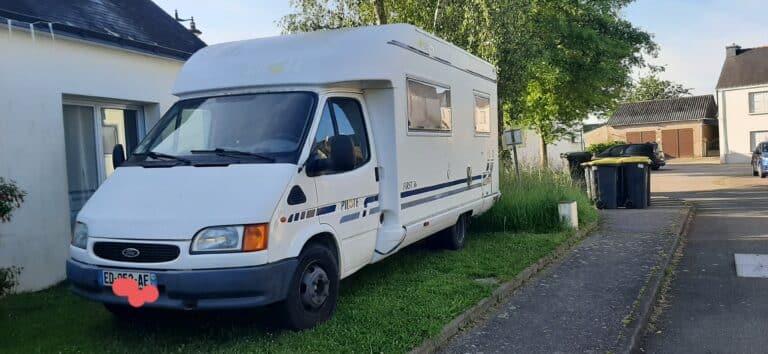 Camping-car blanc garé près de maisons.