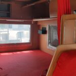 Intérieur d'une caravane aménagée avec fenêtres et rideaux.