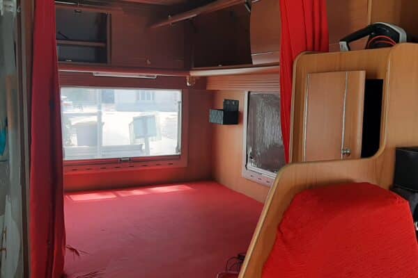 Intérieur d'une caravane aménagée avec fenêtres et rideaux.