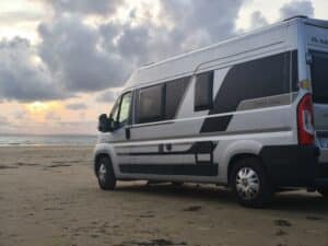 Van stationné sur la plage au coucher du soleil