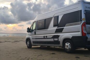 Van stationné sur la plage au coucher du soleil
