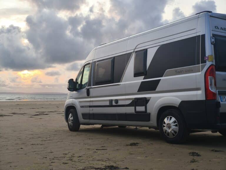 Van stationné sur la plage au coucher du soleil